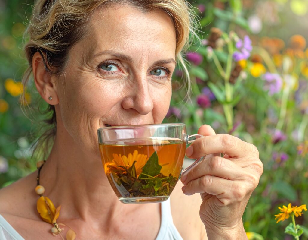 Primo piano di una donna che assapora un infuso caldo di erbe naturali in un giardino fiorito